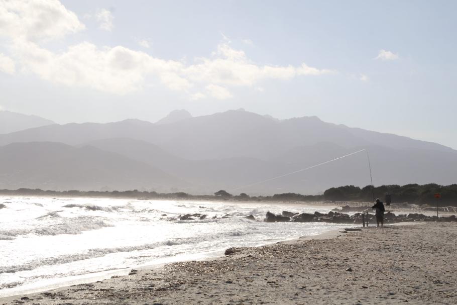 Es ist stürmisch. Außer einem Angler ist der Strand menschenleer.