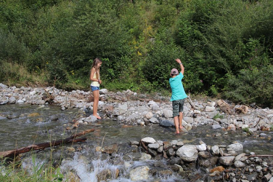 Die Kinder kühlen sich die Füße im Bach.