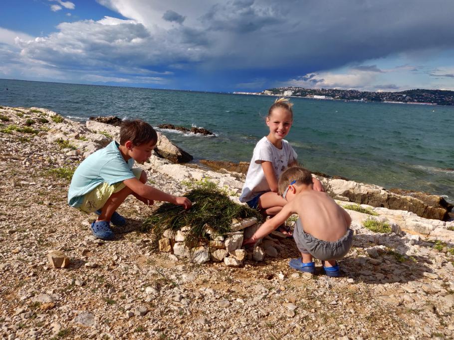 Die Kinder bauen am Strand eine tolle Steinhütte.