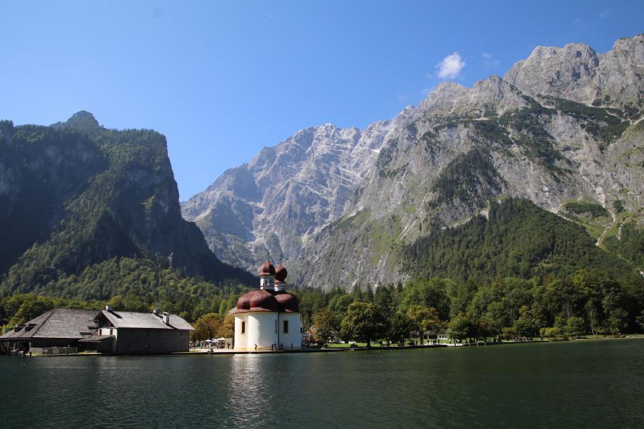Hinter der Kirche St. Bartholomä ragt der Watzmann auf, an dem sich übermütige Kletterer jährlich traditionell zu Tode stürzen.