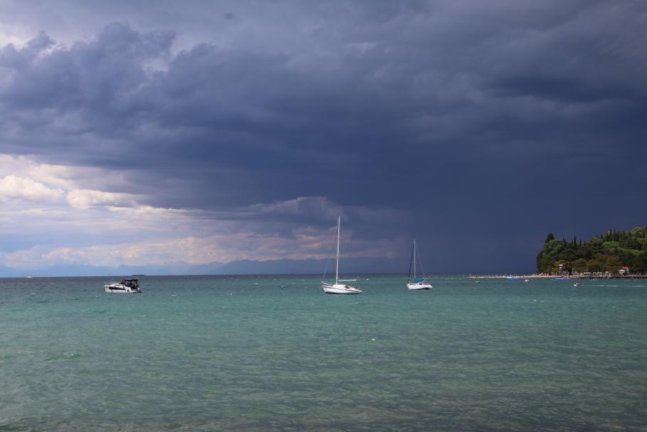 Die Boote und der Strand sind noch in der Sonne, während es dahinter schon ordentlich schüttet