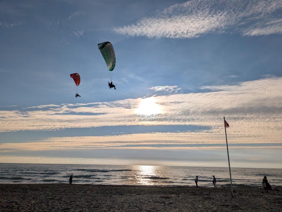Zwei Paragleiter düsen über den Strand